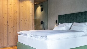 A modern bedroom with a wooden wardrobe, a green upholstered bed, and a concrete wall.