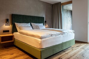 Une chambre d’hôtel moderne avec un grand lit, un plancher en bois et une vue par la fenêtre, qui est dotée de rideaux.