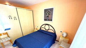 Ein Schlafzimmer mit einem Bett, einem Sessel, einem Nachttisch, einem Globus und einem Bild an der Wand.