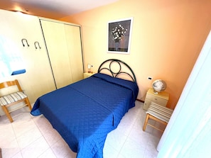 Un dormitorio con cama, una silla, una mesita de noche, un globo terráqueo y un cuadro en la pared.
