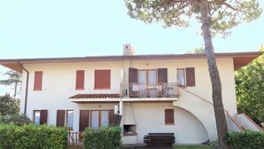 A two-story building with a balcony, a chimney, and a small garden area. - Apartment in a Villa With Garden (San Michele al Tagliamento)