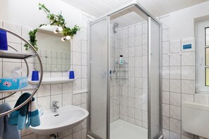 A modern bathroom with a glass-enclosed shower, a sink, and a mirror.