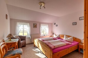 A bedroom with a wooden bed, a desk, a chair, and two windows with curtains. - Apartment 'Fewo Springflot' with Shared Terrace, Shared Garden and Wi-Fi (Pellworm)
