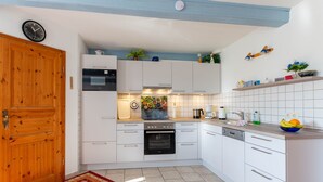 Una cucina moderna con mobili bianchi, una porta in legno, un orologio e uno schienale piastrellato.