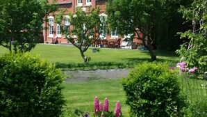 A large brick building with a tower, surrounded by lush greenery and a well-maintained lawn.