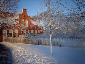 Un paysage enneigé avec une maison en briques et un arbre.