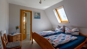 Un dormitorio con cama, una silla, un escritorio, una ventana y una puerta.