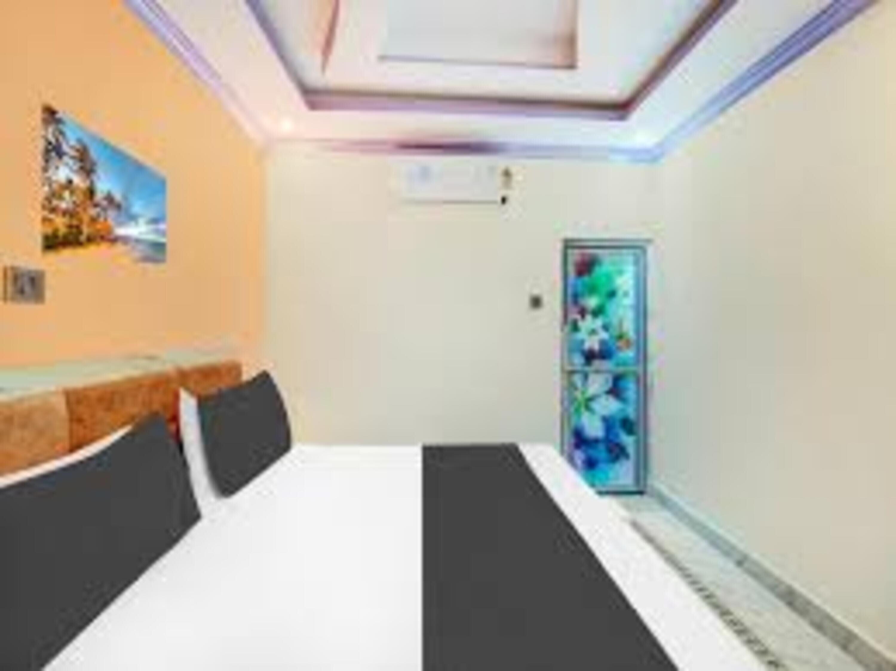 A hotel room with a bed, a small desk, a chair, a window, and a door.