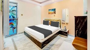 A modern hotel room with a large bed, a marble floor, a painting on the wall, and a nightstand with a lamp. - Raj Palace Guest House (Patna)