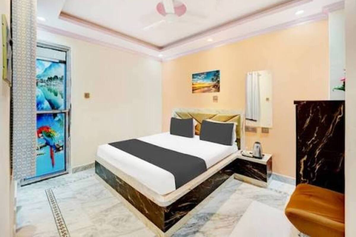 Una habitación de hotel moderna con una cama grande, suelo de mármol, un cuadro en la pared y una mesita de noche con una lámpara.