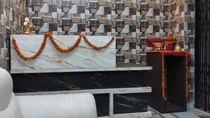A reception area with a 'RAJ PALACE' sign, a statue, and a decorative garland. - Raj Palace Guest House (Patna)
