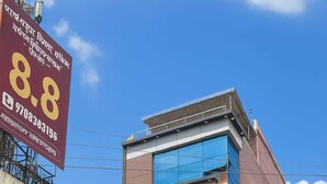 A multi-story building with various commercial establishments on the ground floor, including a bank, a telecom service provider, and a hotel named "Rai Palace". - Raj Palace Guest House (Patna)