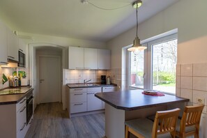 A modern kitchen with white cabinets, a central island, and a window providing natural light.