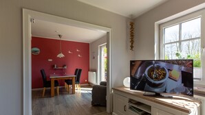 Una cucina moderna con zona pranzo, televisione e finestra vista alberi.