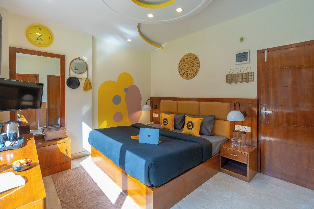 A bedroom with a bed, bedside tables, a TV, and a clock on the wall.
