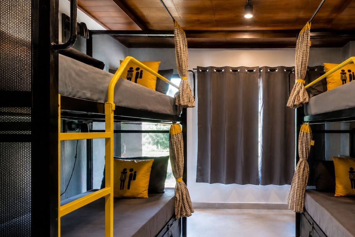 Une chambre avec un lit superposé, une fenêtre, des rideaux et un oreiller sur le lit.