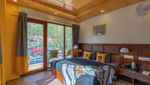 Un dormitorio con una cama grande, cabecera de madera y vistas a un balcón con mobiliario exterior.