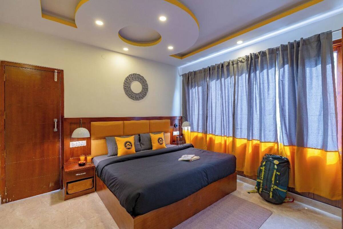 Une chambre d’hôtel avec un grand lit, une armoire en bois, une table de chevet avec une lampe et une fenêtre avec des rideaux.