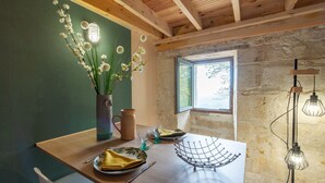 A wooden dining table with a vase of white flowers, a copper mug, and a metal wire basket.