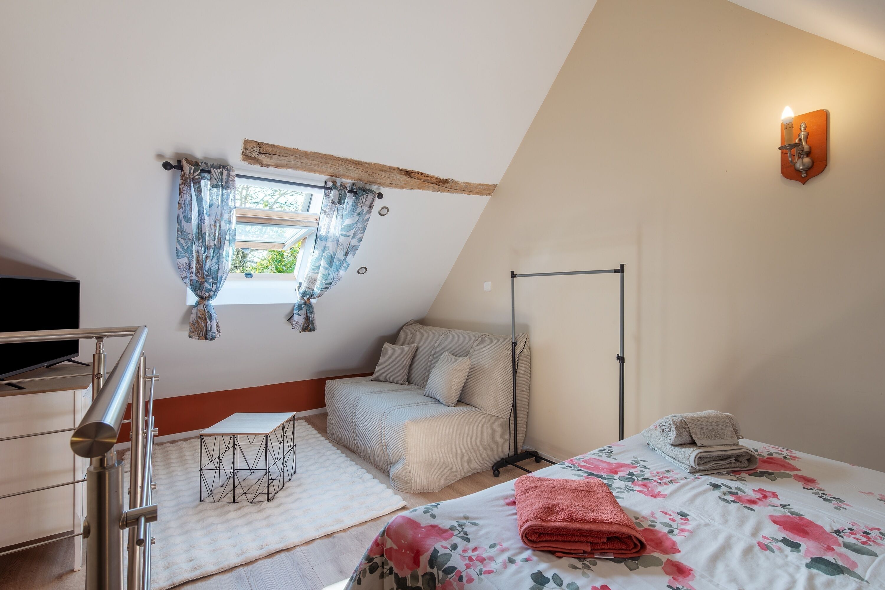 Un dormitorio con cama, sofá, televisor y ventana con cortinas.