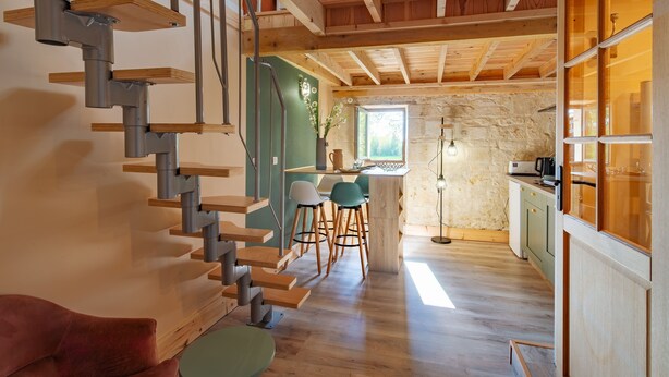 A modern interior with a wooden staircase, a kitchen area, and a dining space with bar stools.