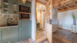 A kitchen with teal cabinets, a microwave, and a patterned backsplash.
