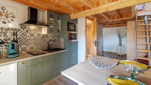 A kitchen with green cabinets, a wooden ceiling, and a dining area with a table set for two.