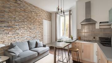 Une cuisine moderne avec un mur en pierre, un canapé gris et un coin bar.