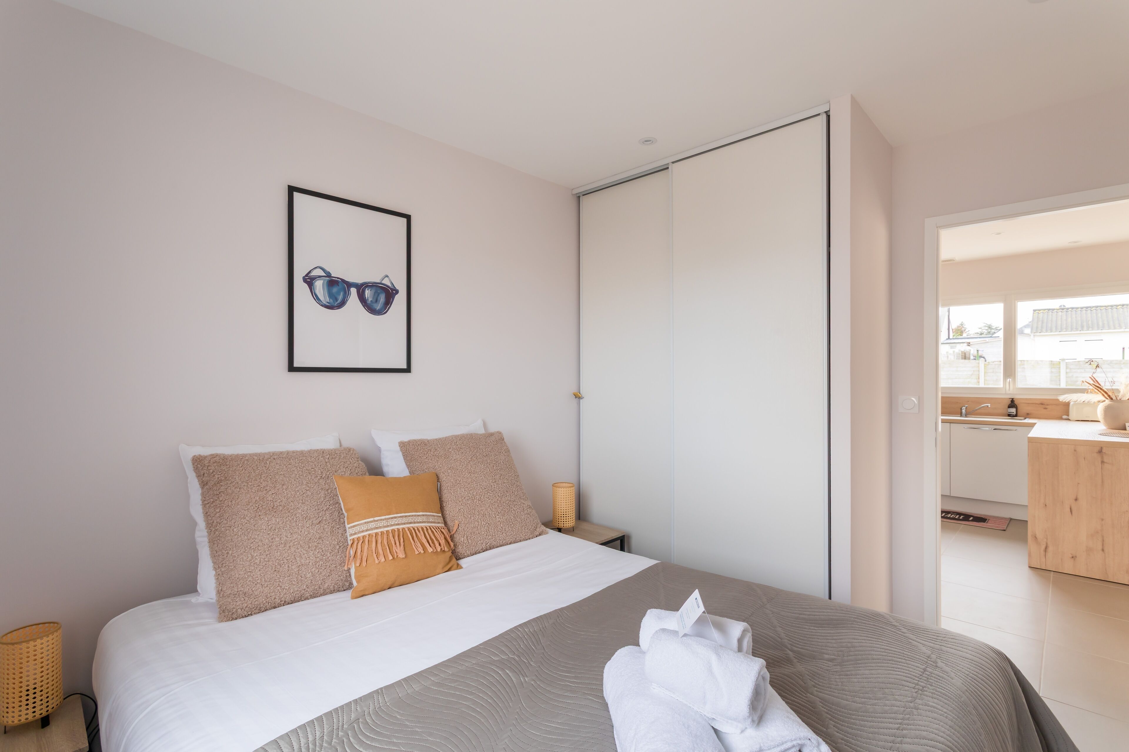 Un dormitori modern amb un llit gran, un quadre al mur i una porta corredissa que condueix a un bany.