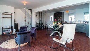 A modern kitchen with a dining area, wooden flooring, and a staircase leading to another level.