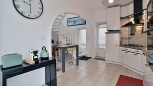 Una cocina moderna con armarios blancos, encimera negra y un reloj en la pared.