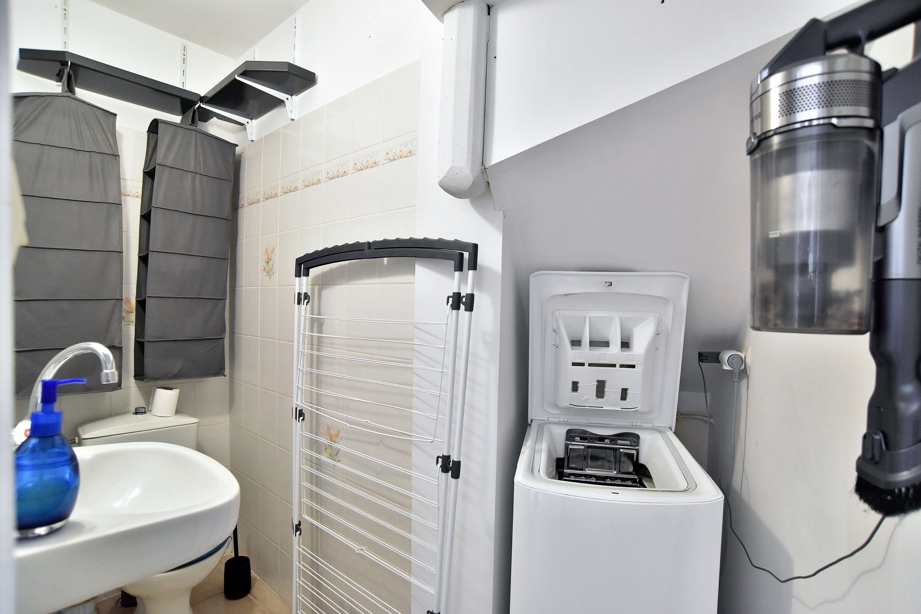 Une petite salle de bain comprenant un lavabo, un porte-serviettes et un appareil combiné lave-linge et sèche-linge de dimensions réduites.