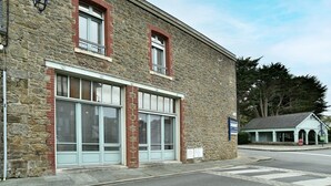 Un edificio de piedra con ventanas grandes y una estructura pequeña adosada.