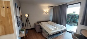 Un dormitorio con cama, mesita de noche, lámpara y vistas al exterior.