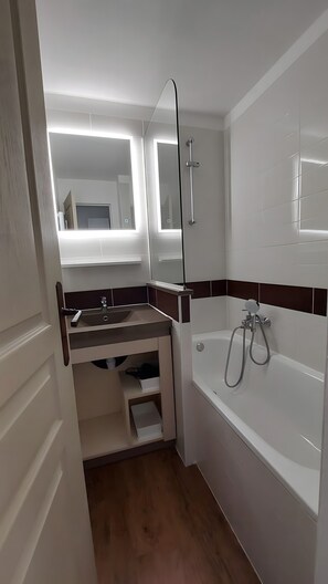 Un baño moderno con bañera, espejo y ducha.