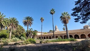 Un patio con palmeras, un edificio con arcos y una torre.