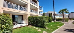 Un hotel de varios pisos con balcones, un césped bien cuidado y una palmera.