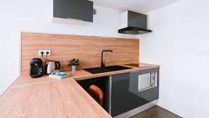 Cocina moderna con encimera de madera, pileta negra y lavavajillas integrado.