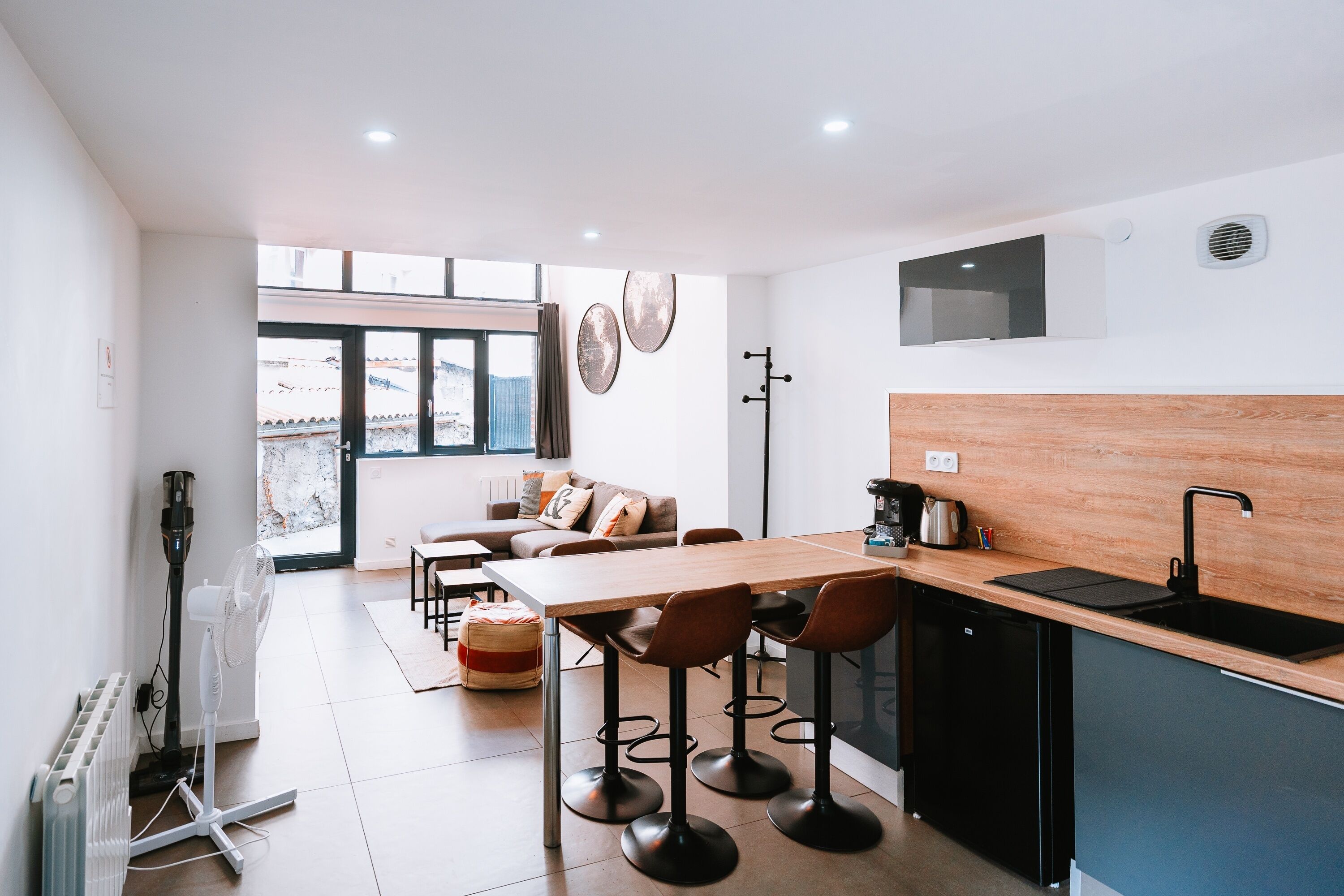 Une cuisine moderne avec un plan de travail en bois, un évier noir et un coin repas comprenant une table et des chaises.