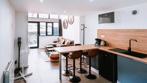 A modern kitchen with a wooden countertop, black sink, and a dining area with a table and chairs.