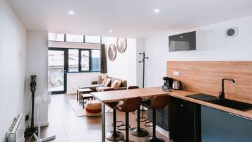 Une cuisine moderne avec un plan de travail en bois, un évier noir et un coin repas comprenant une table et des chaises.