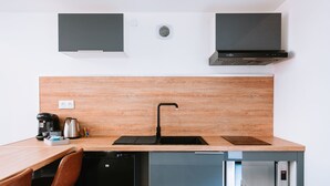 A compact kitchen with a wooden countertop, a black sink, a built-in microwave, and a dishwasher.
