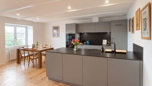 A modern kitchen with grey cabinetry, a central island, and a dining area with wooden chairs.