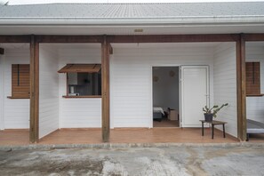 Un bâtiment blanc avec des poutres en bois, une véranda et une petite table sur laquelle est posée une plante en pot.