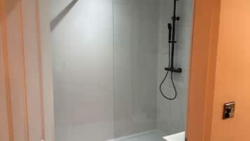 Une salle de bain moderne avec une douche à parois de verre, un lavabo blanc et un sol carrelé.