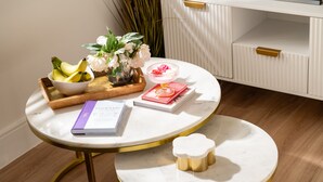 A round table with a book, a bowl of fruit, and a vase of flowers. - Stargazing Studio with Private Hot Tub (Blandford Forum)