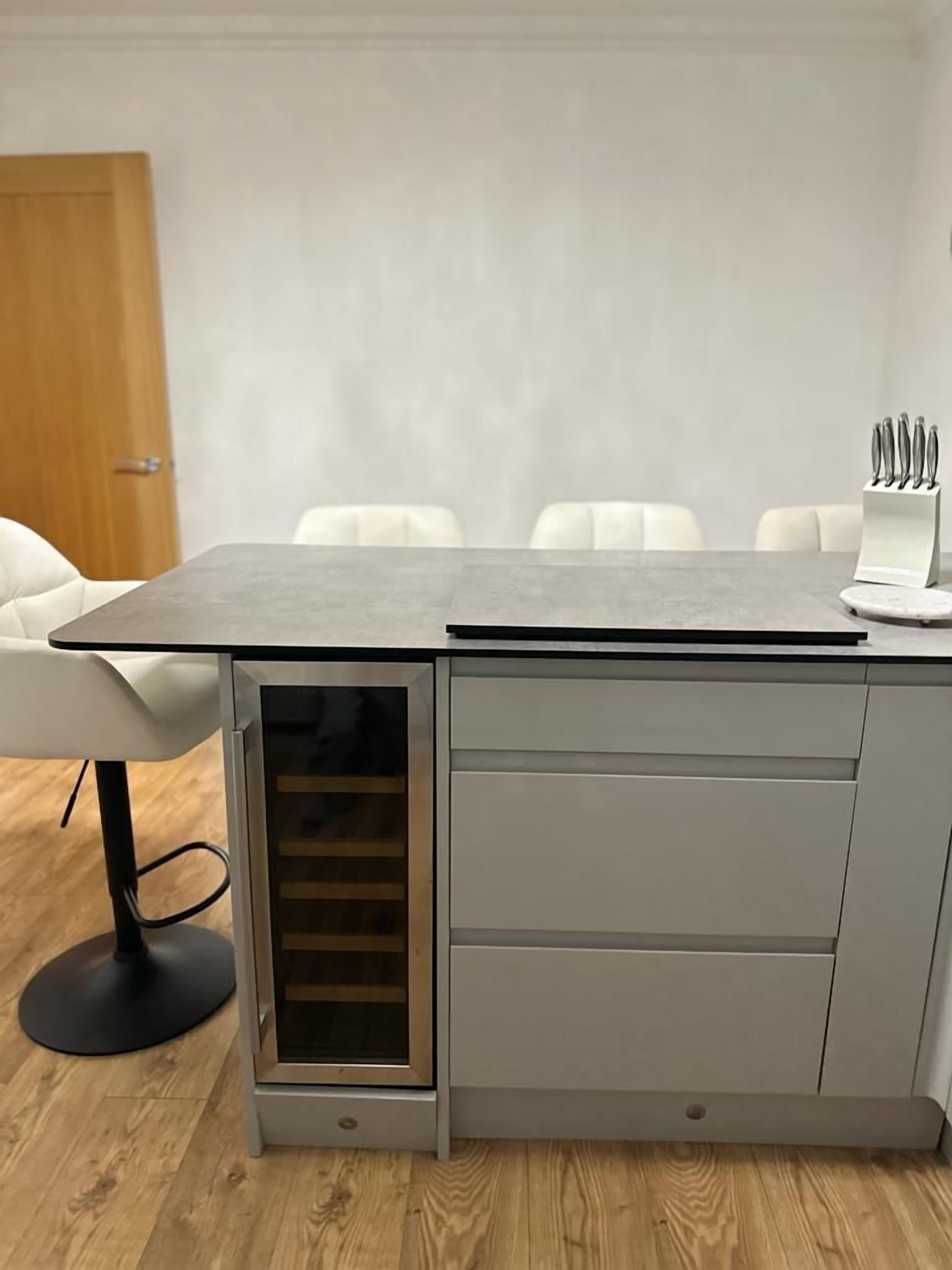 A modern kitchen with a built-in oven, a countertop, and a knife block.
