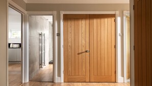 Un pasillo con suelo de madera y una puerta doble de madera.