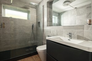 Un bagno moderno con box doccia in vetro, un water bianco e uno specchio grande sopra un lavabo.