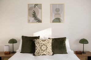 A bed with two pillows, a bedside table with a lamp, and two framed artworks on the wall. - Hambledon Hill Cottage with Private Hot Tub (Blandford Forum)